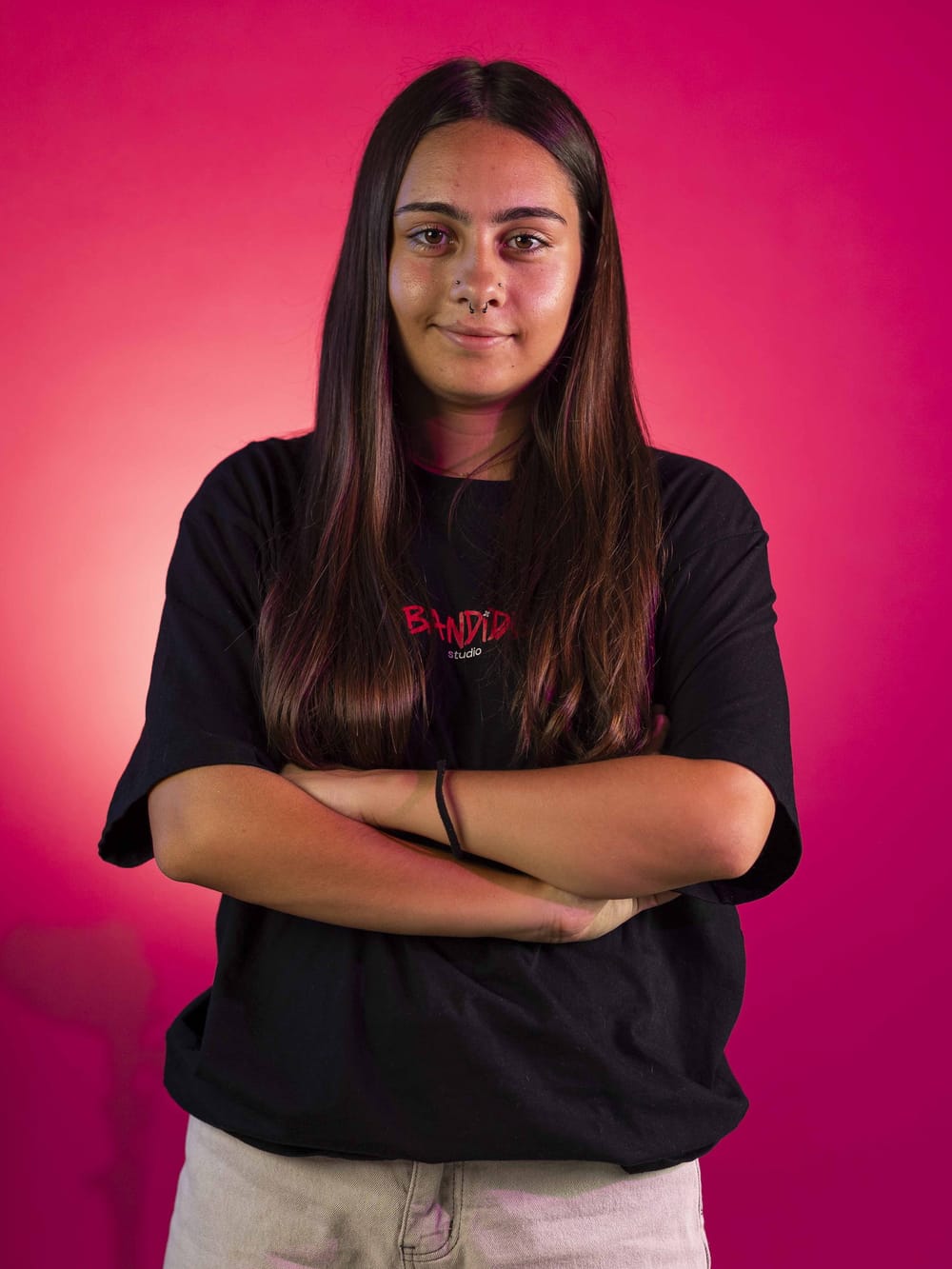 Retrato de Iris sobre fondo rosa, con la camiseta de Bandido Studio
